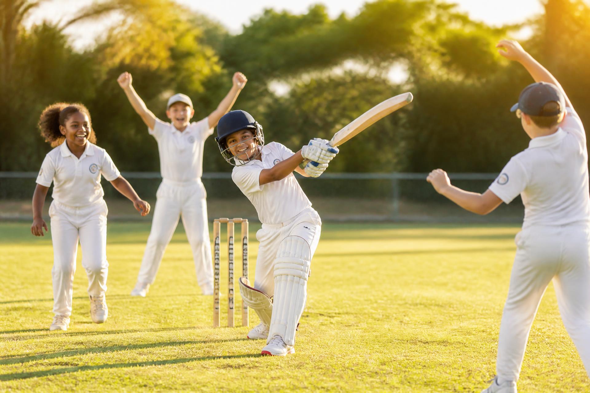 Young cricketers celebrating on a sunlit pitch